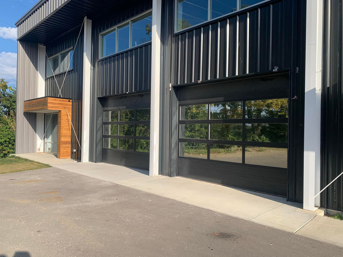 Full-view glass commercial garage doors on a black metal building in central Kentucky