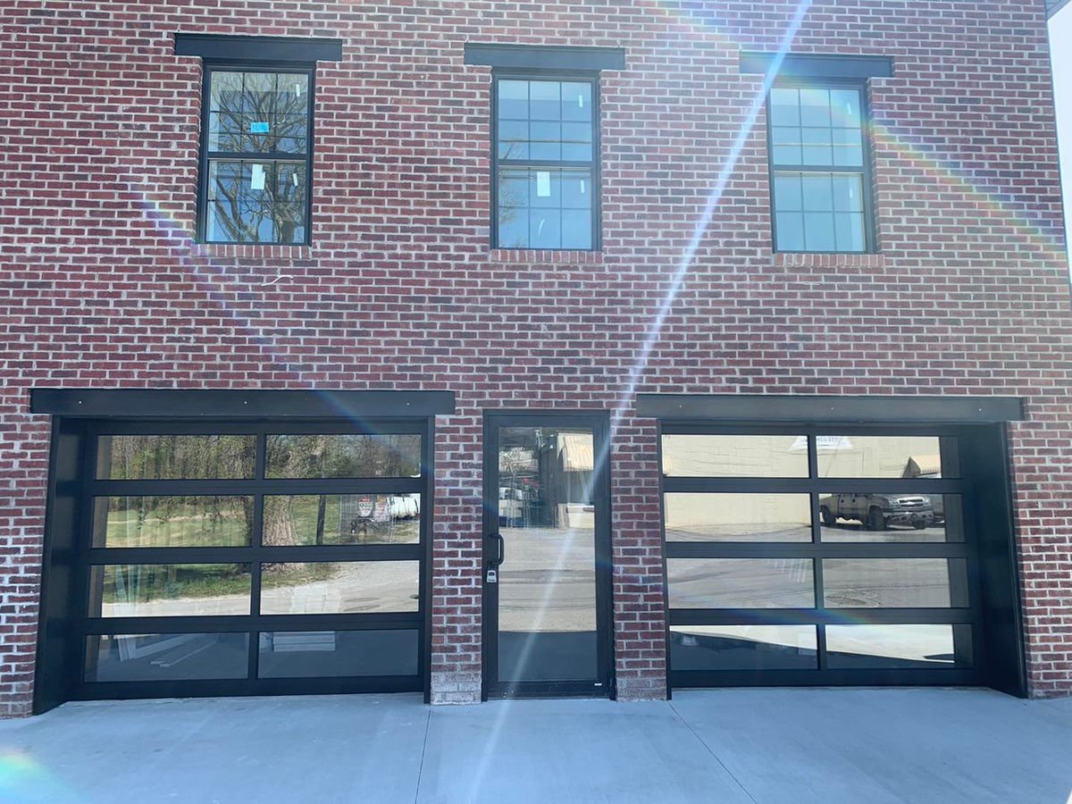 Full-view glass garage doors installed on a brick building by EZ Open